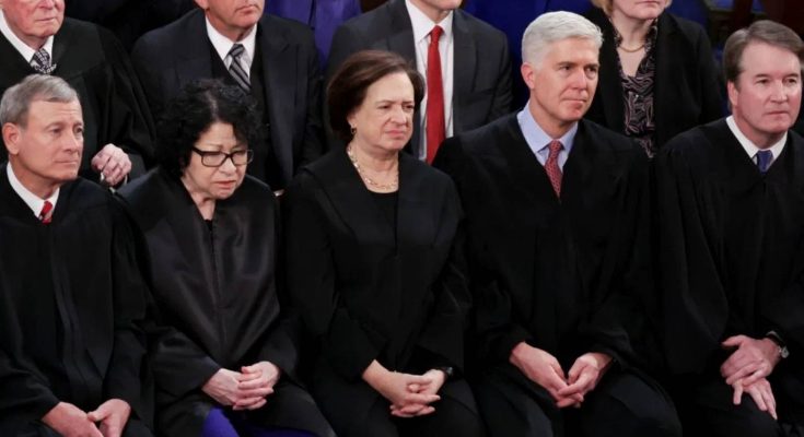 Five Supreme Court justices in black robes seated in a row, with other officials