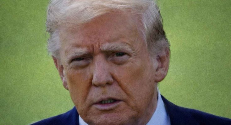 Close-up of a man with blond hair wearing a dark suit and red tie against a green