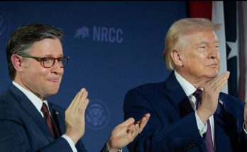 Two men in suits clapping at a political event with NRCC branding in the background