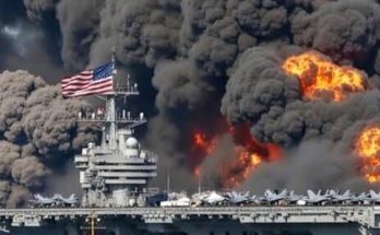 Aircraft carrier with American flag on fire with thick black smoke and orange flames